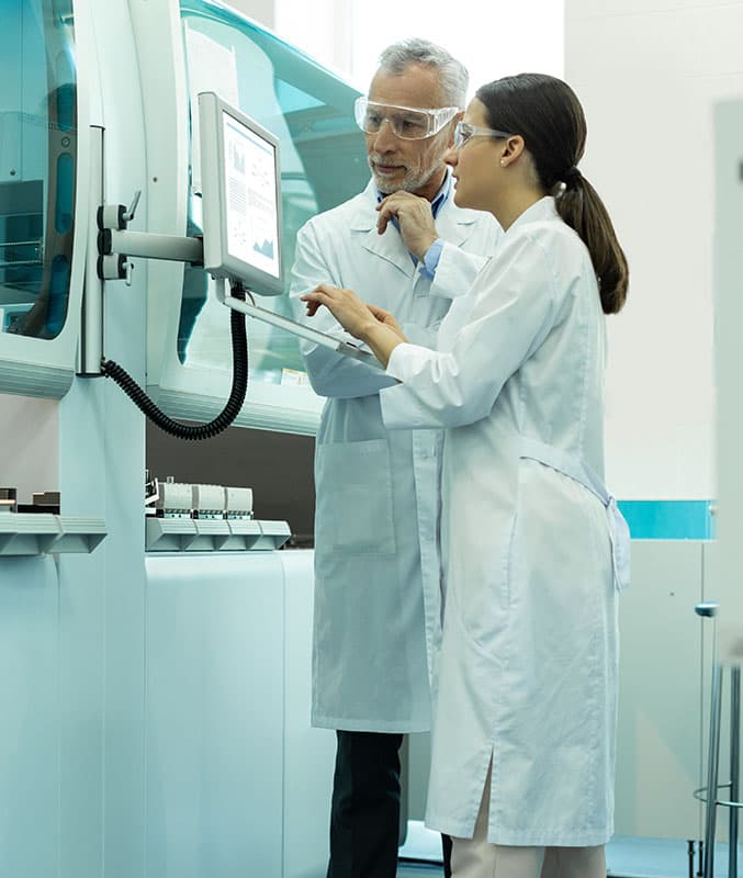 Scientists reviewing data on a sequencer screen; biological sample being managed by a scientist